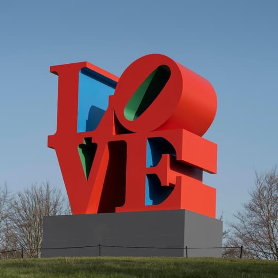 Red, blue and green LOVE sculpture on a grass mound at YSP.