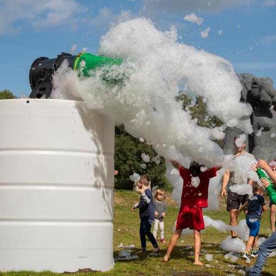 A group of people playing in a cloud of foam outdoors