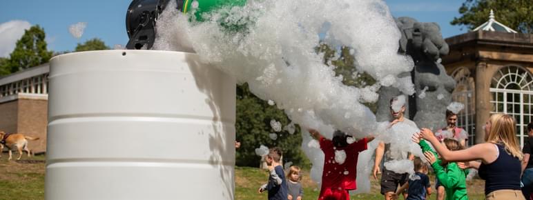 A group of people playing in a cloud of foam outdoors