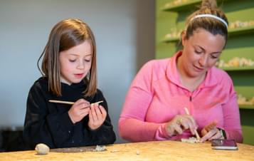 An adult and child making wax animal models