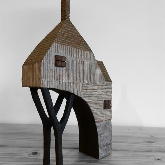 Miniature wooden house with chimney and stilts.