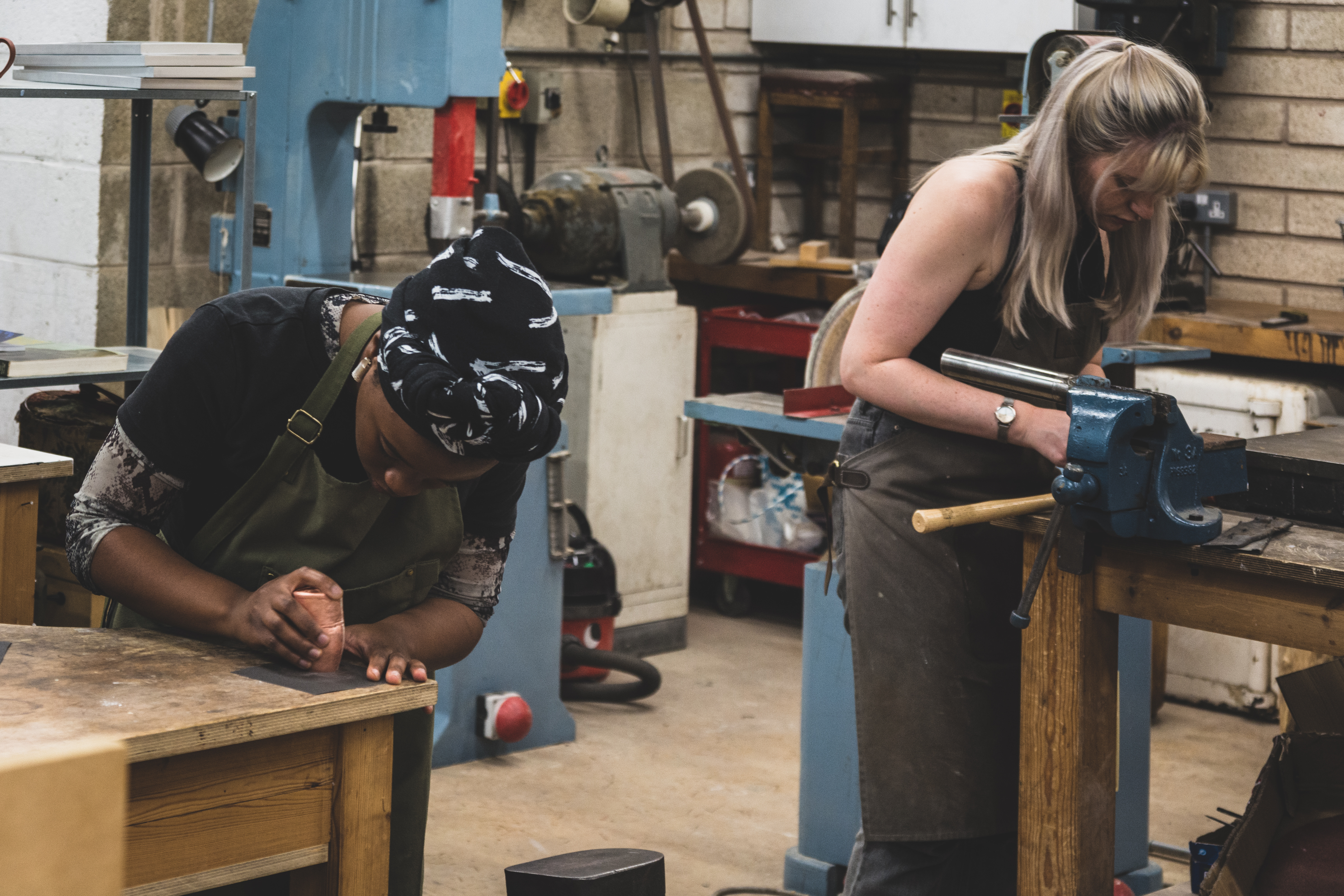 Two women working with carving tools in a workshop space