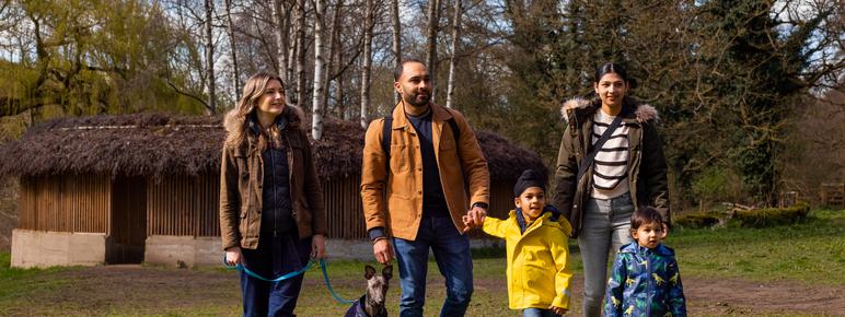 a family with two children and friend with a dog walking near an artwork outside at YSP