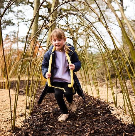 A child running through a willow tunnel