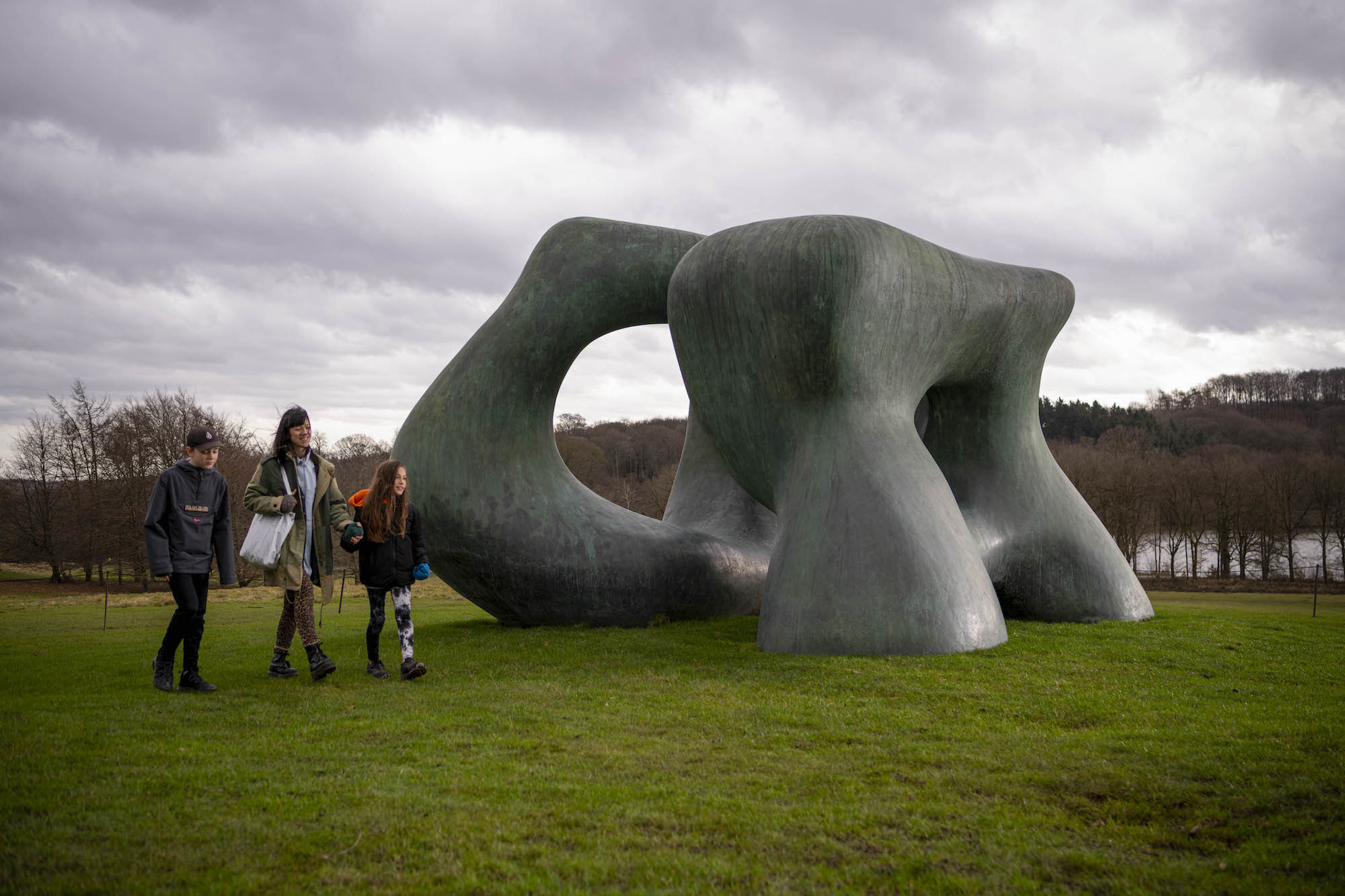 People walking past a Henry Moore sculpture in the country park.