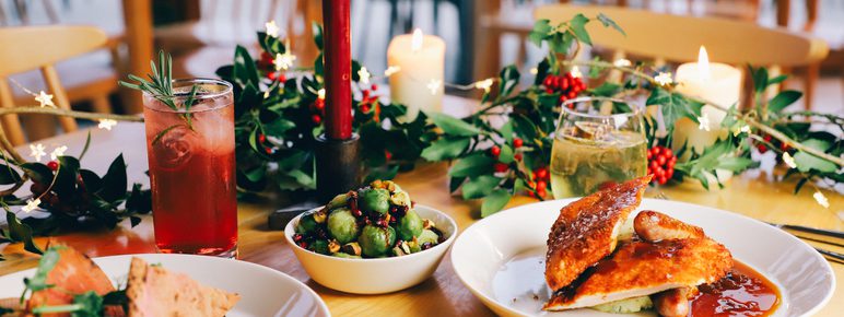A table with plates of festive food and decorative foliage.