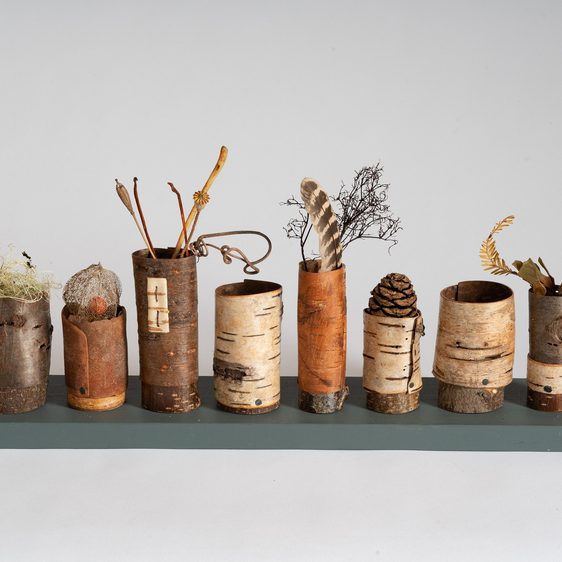 A shelf displaying a series of vessels made from bark and other natural materials.
