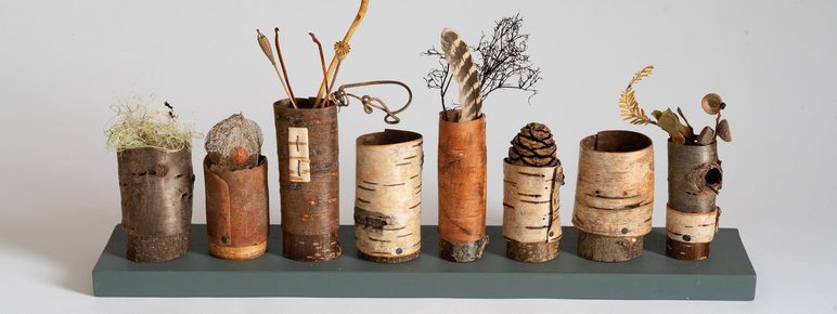 A shelf displaying a series of vessels made from bark and other natural materials.