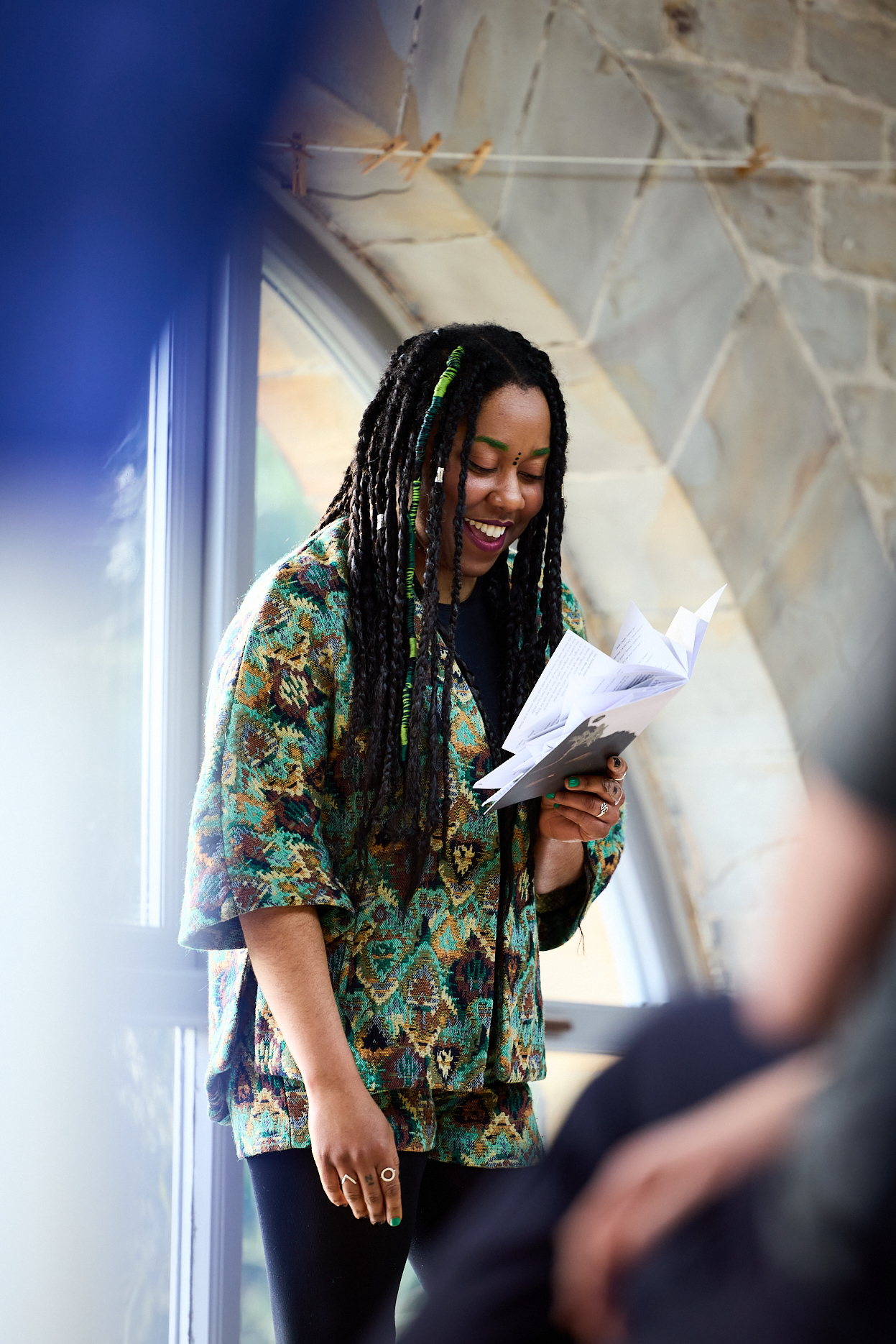A black woman with braided hair smiling while reading from a booklet