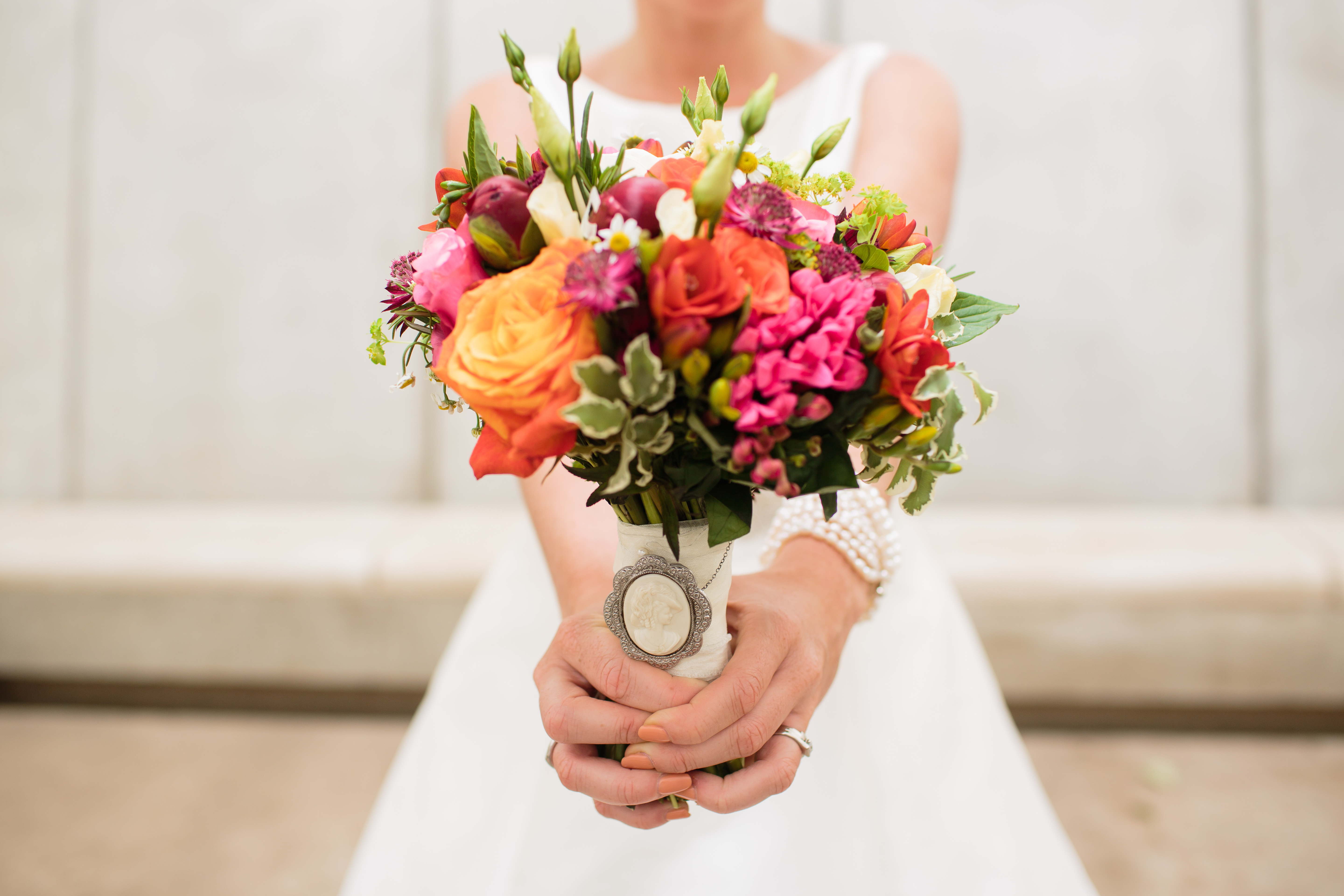 A bride holding a bouquet of orange and pink flowers.