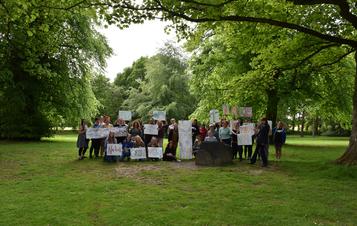 A large group of people holding hand decorated banners under the trees at YSP.