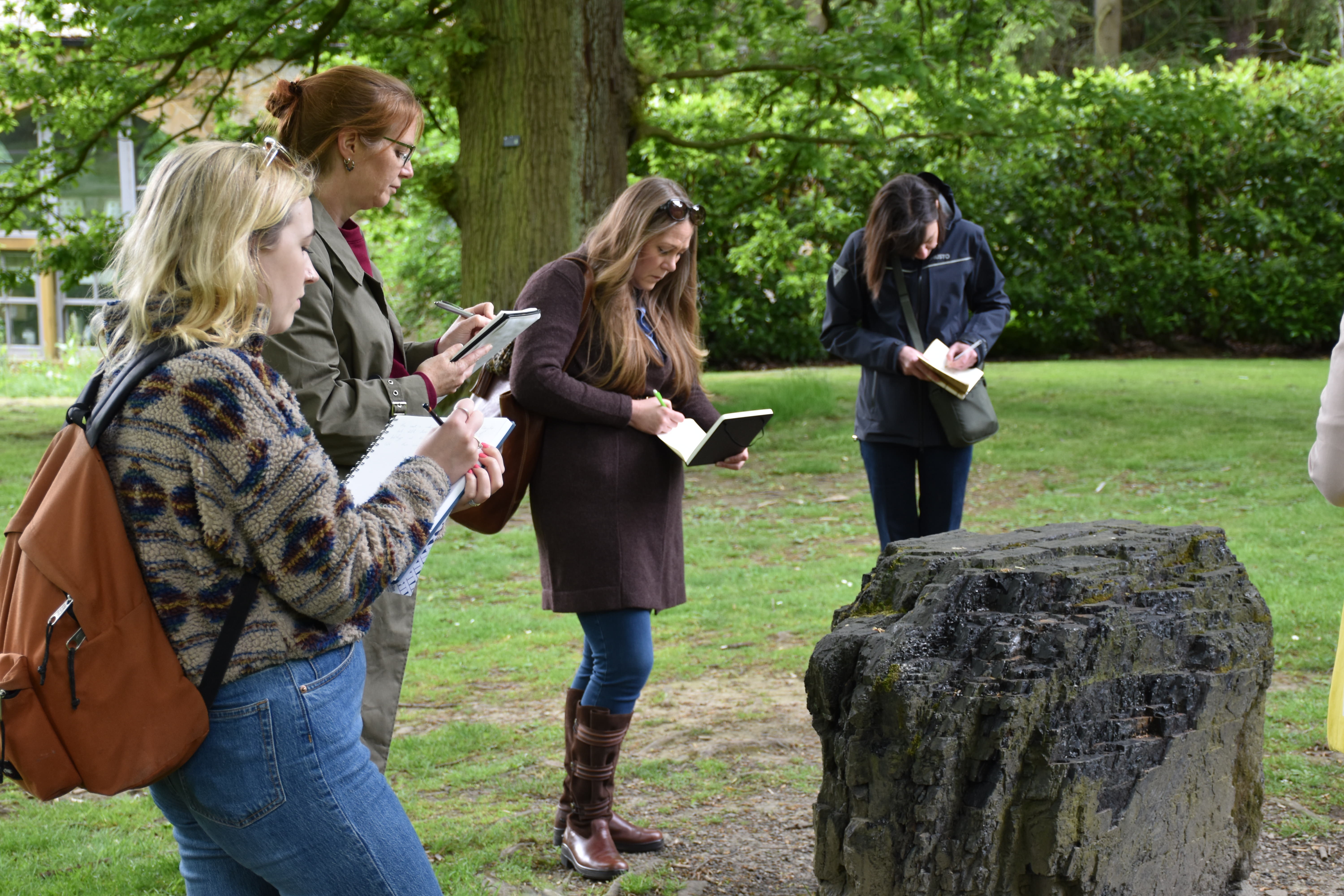Four women taking notes stood around a sculpture taking notes.