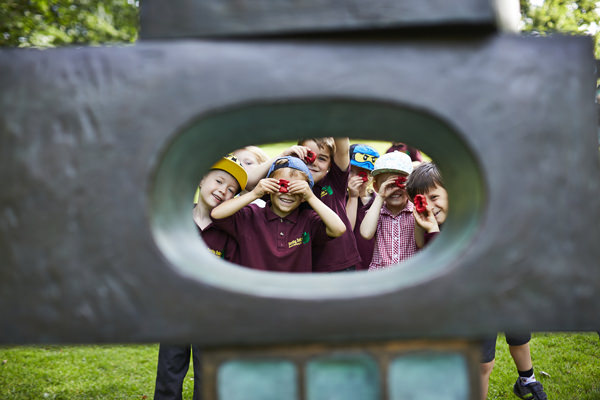A group of young children looking through the eye of a sculpture