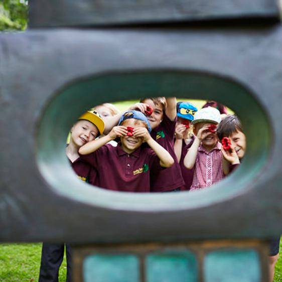 A group of young children looking through the eye of a sculpture