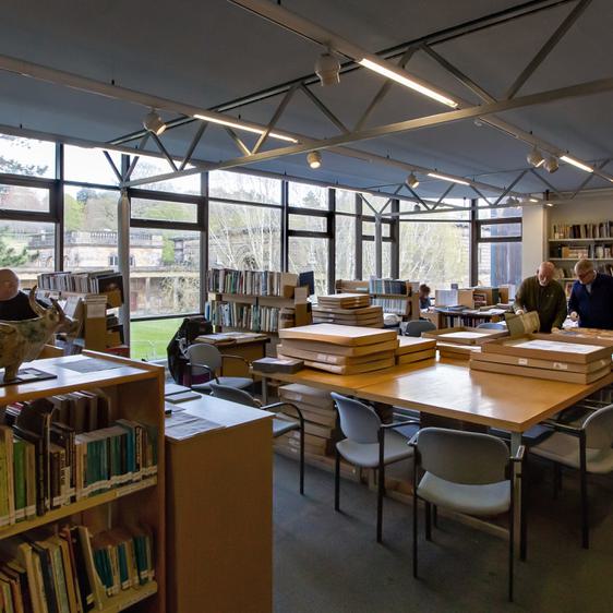 Four people stood amongst bookshelves and tables in the National Arts Education Archive.