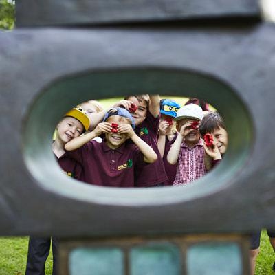 A group of young children looking through the eye of a sculpture.