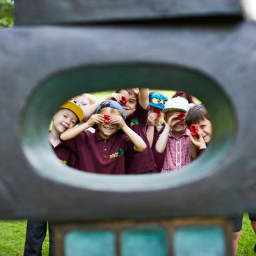 A group of young children looking through the eye of a sculpture.