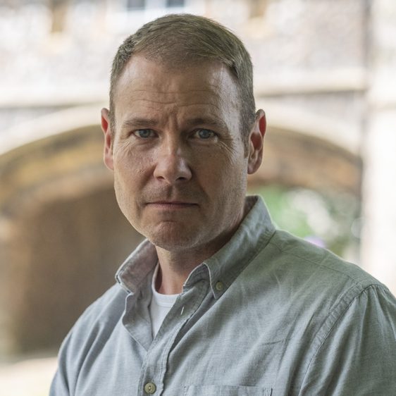 A portrait of a white man wearing a blue shirt.