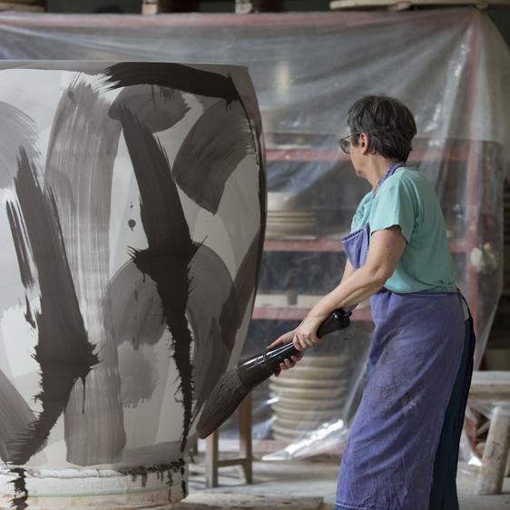 Women decorating a larger than life sized ceramic vase