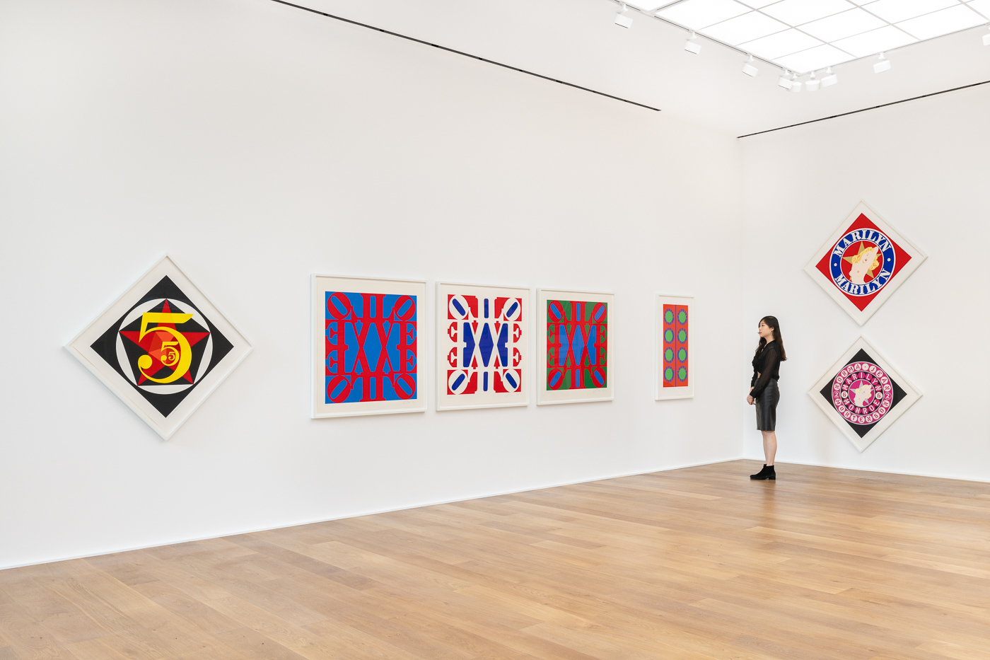 A woman looking at a display of brightly coloured pop art prints in a gallery