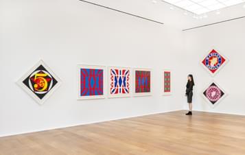 A woman looking at a display of brightly coloured pop art prints in a gallery