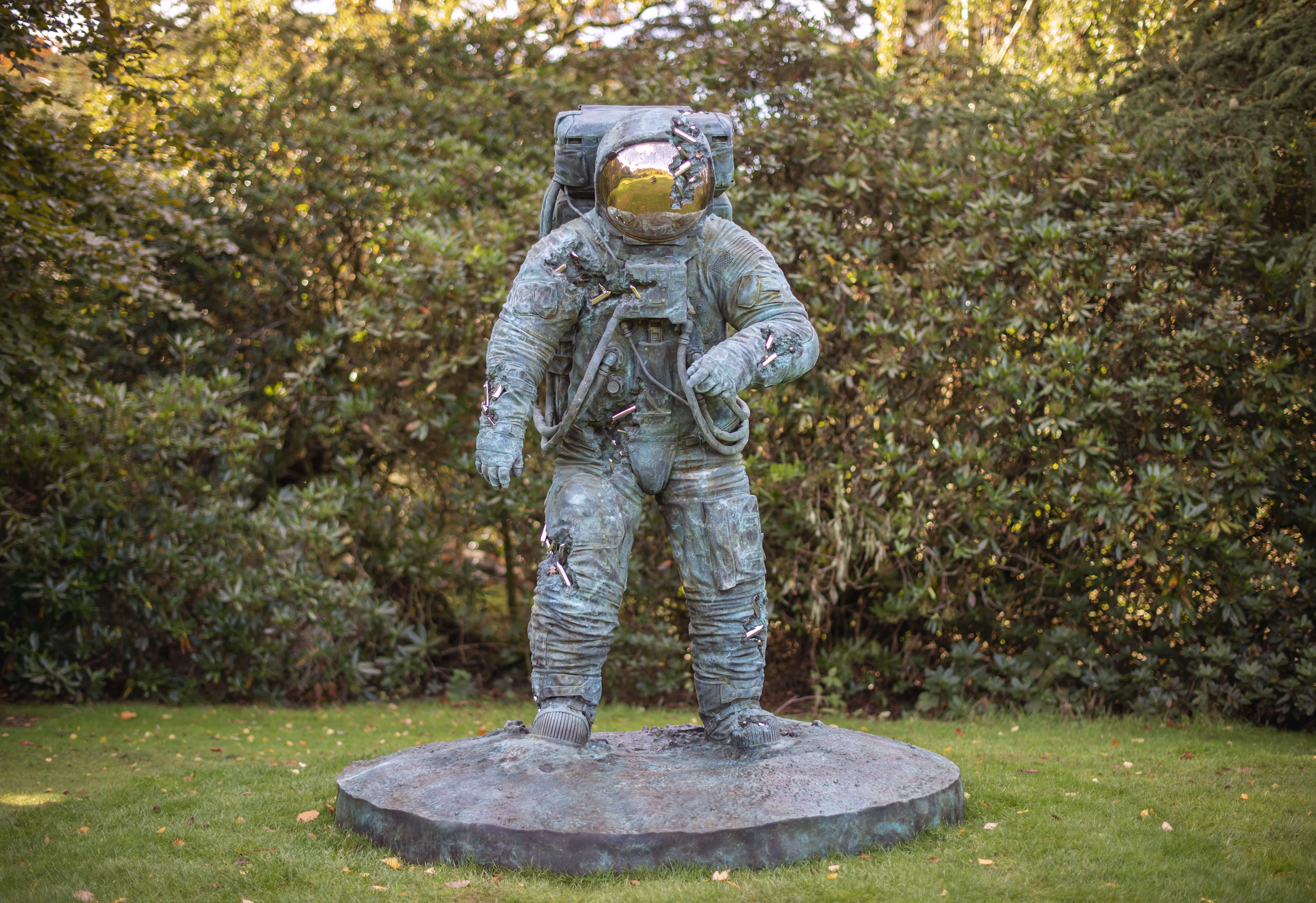 A bronze sculpture of an astronaut with crystal erosions coming out of the bronze.