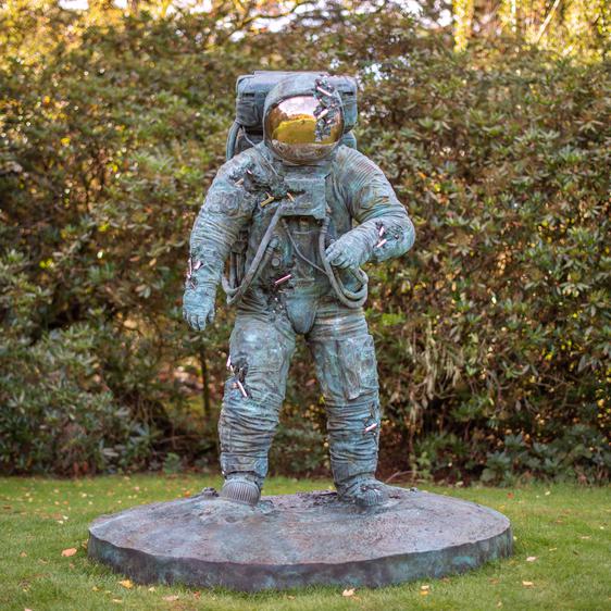 A bronze sculpture of an astronaut with crystal erosions coming out of the bronze.