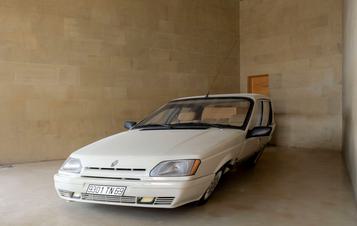 A white slanted car in a gallery space