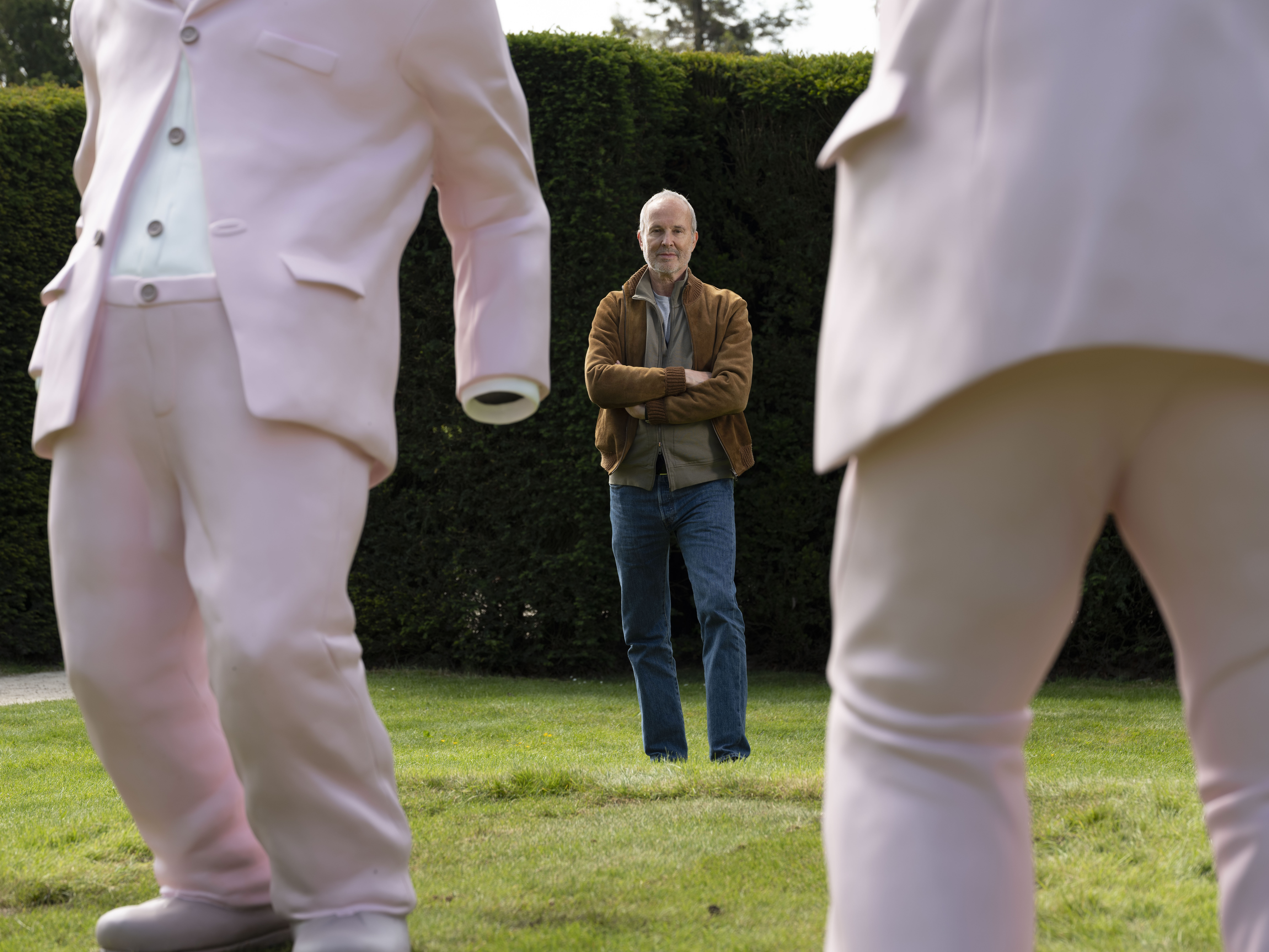 Man in the background, stood in between two pink sculptures of dancing suits