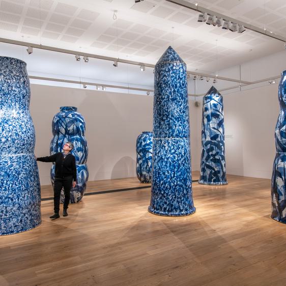 Women looking at larger than life blue ceramic vases