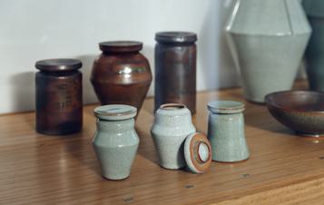 Three small green lidded ceramic vessels and three large brown lidded ceramic vessels