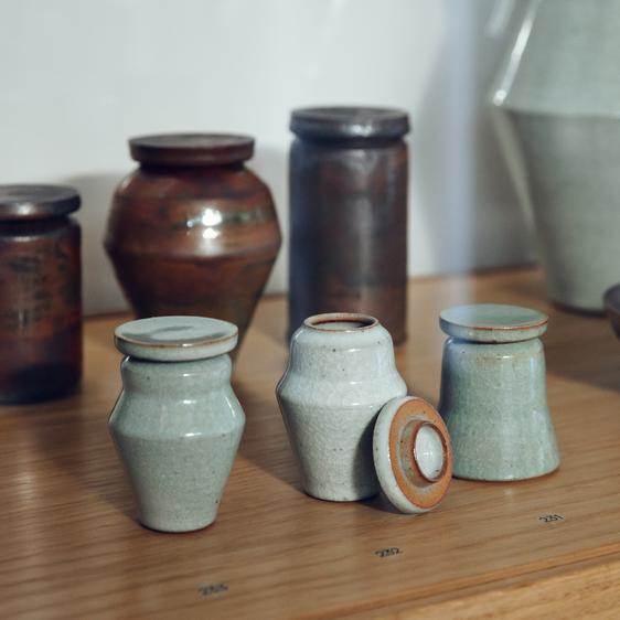 Three small green lidded ceramic vessels and three large brown lidded ceramic vessels