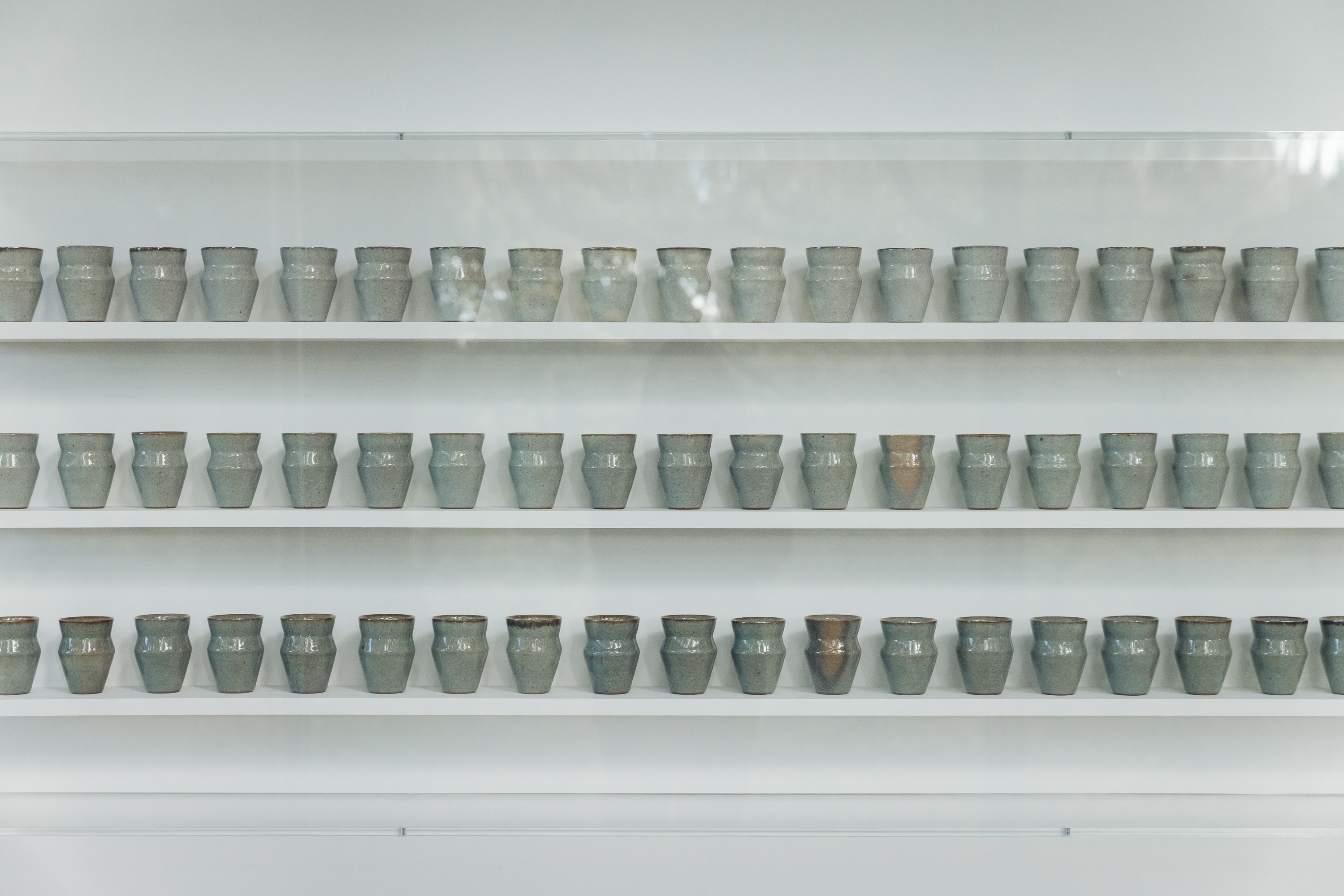 Three shelves filled with small ceramic vessels