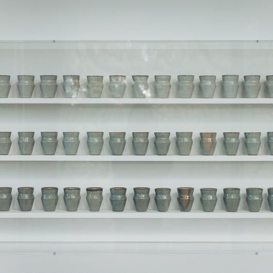Three shelves filled with small ceramic vessels