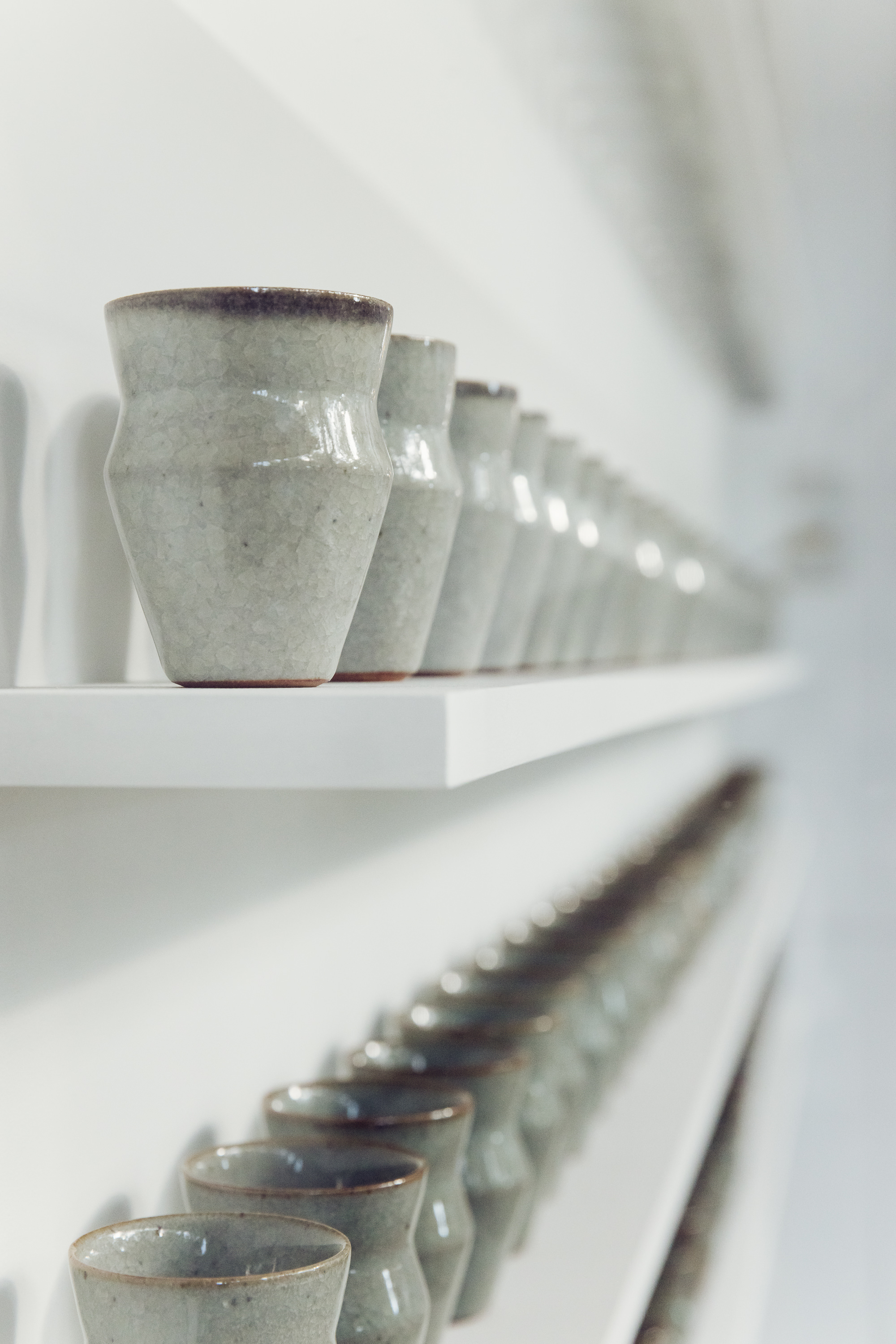 Two shelves stacked with small ceramic vessels