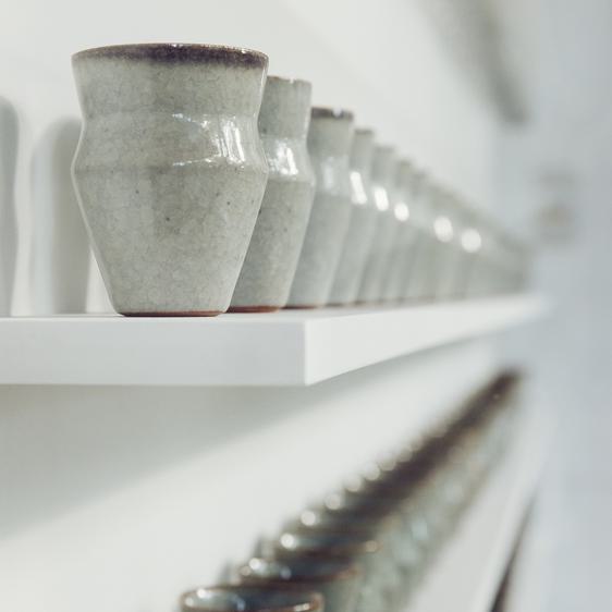 Two shelves stacked with small ceramic vessels