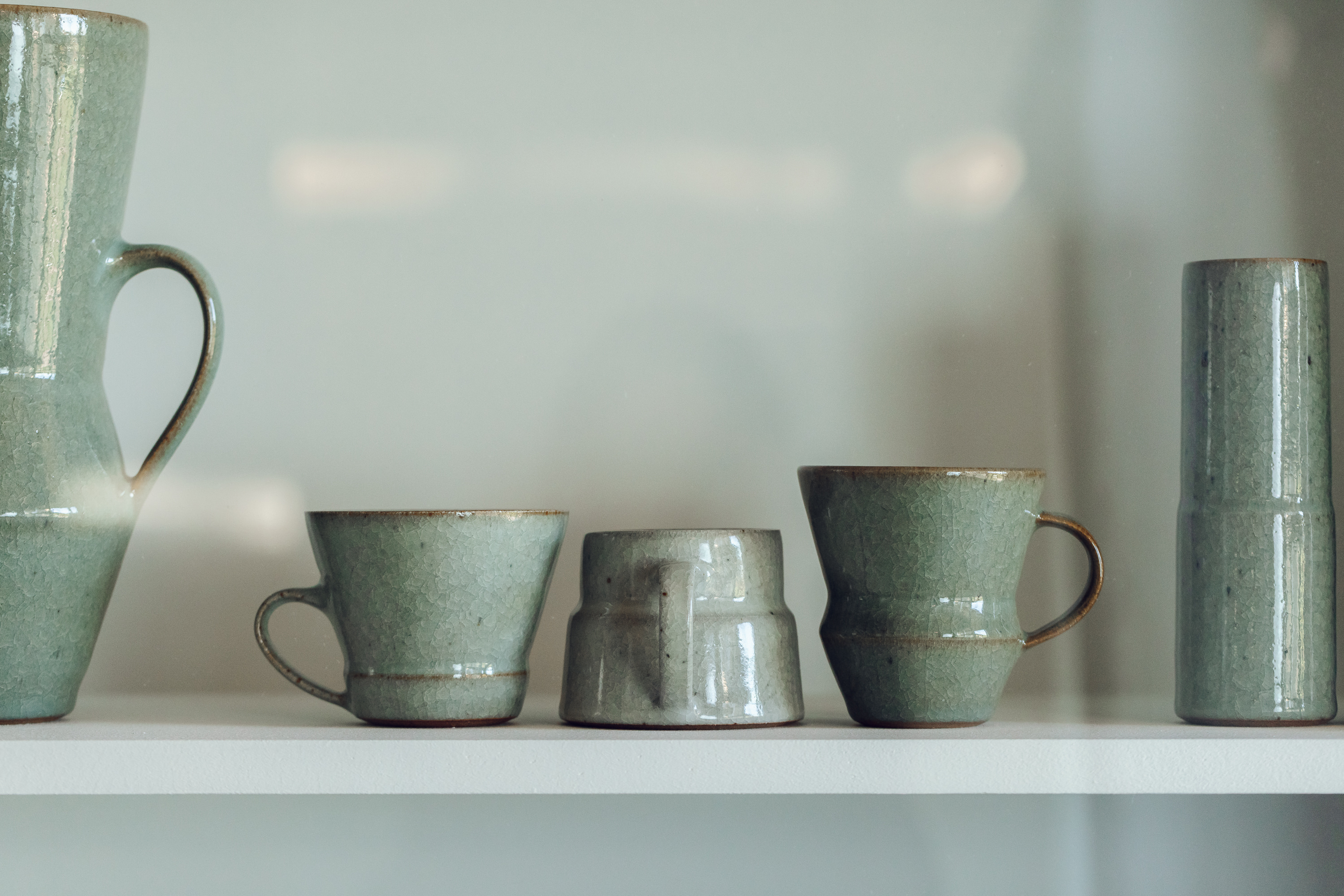 Three ceramic cups on a shelf