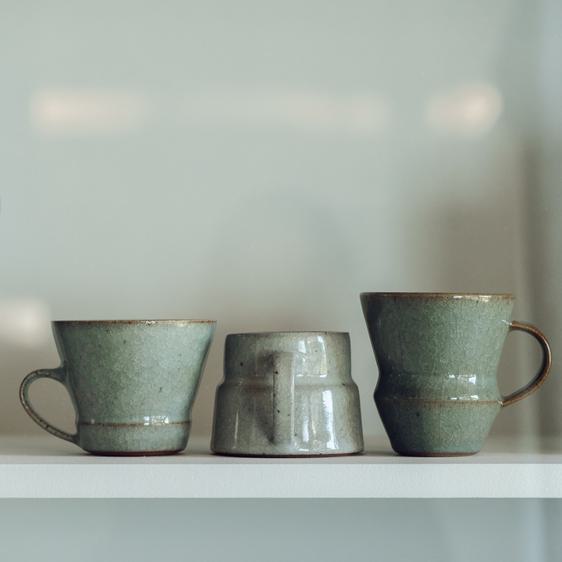 Three ceramic cups on a shelf