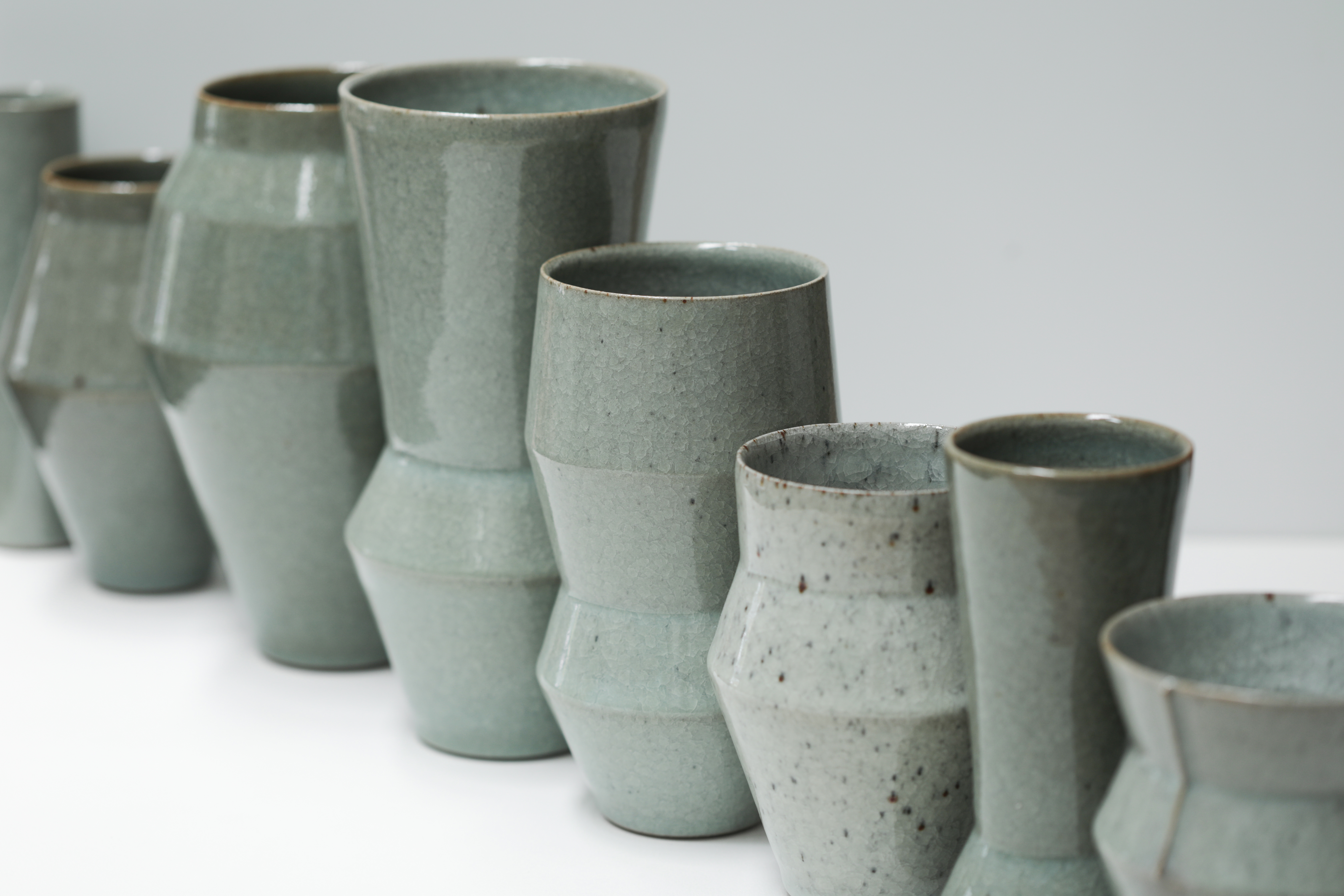 A diagonal row of green-toned ceramic vases