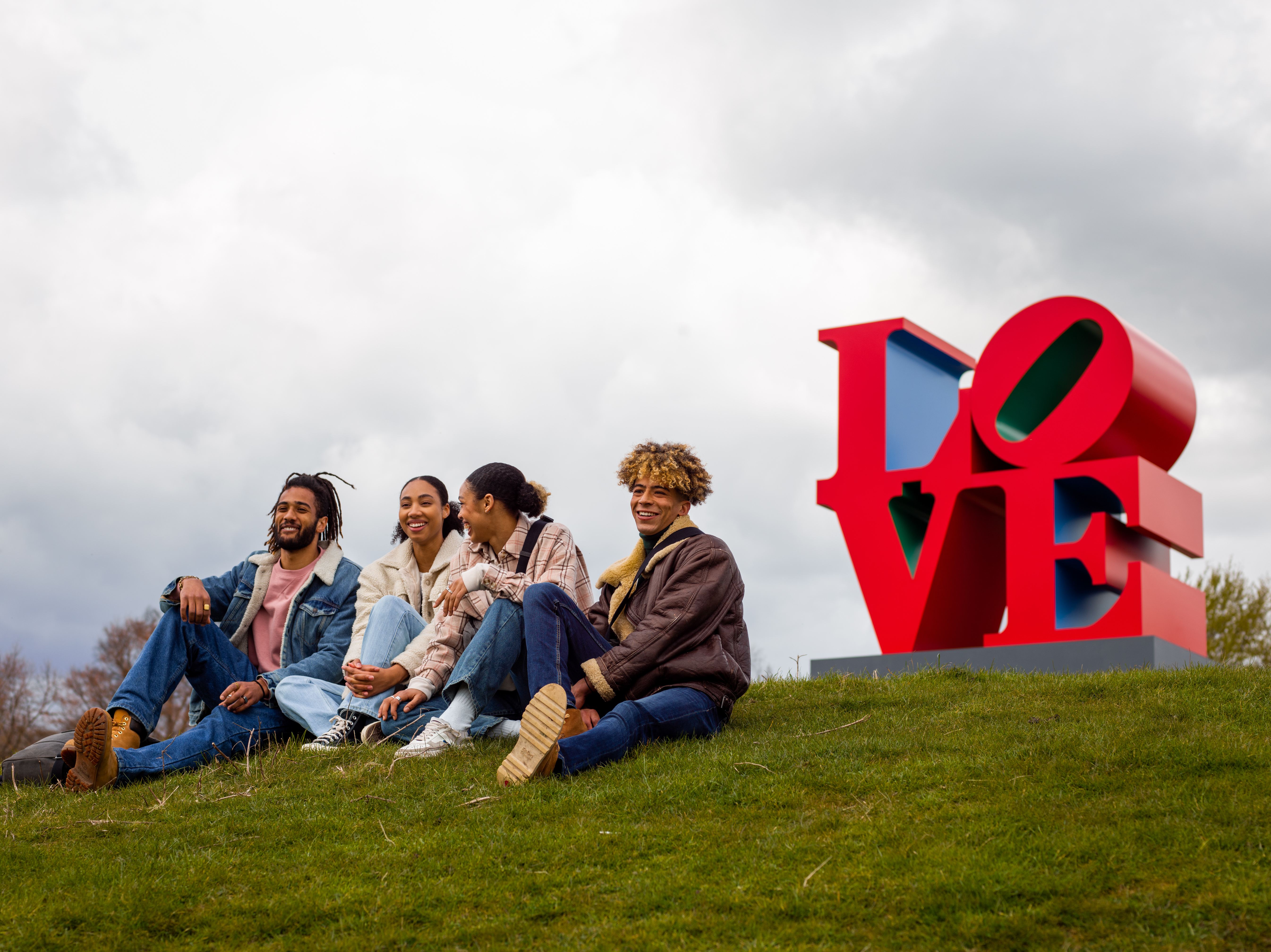 Four friends chatting in front of a red sculpture that reads LOVE