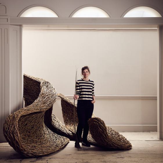 A women stood in a woven willow sculpture