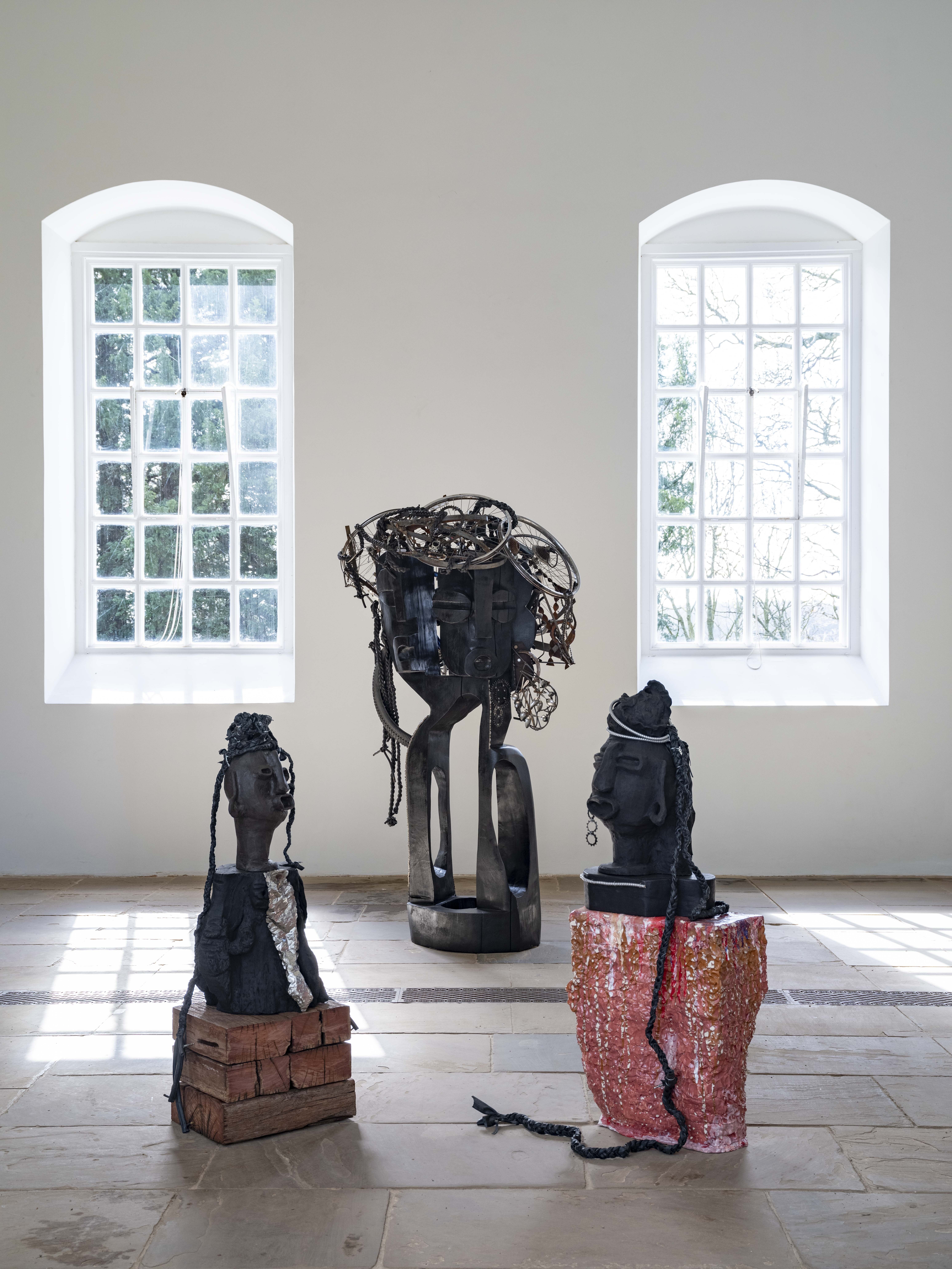 Three large sculptures indoors with two large windows in the background