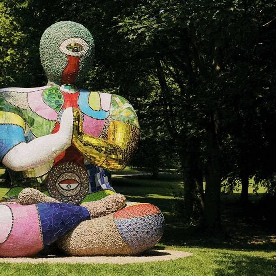 A seated humanoid figure covered in brightly coloured mosaic tiles