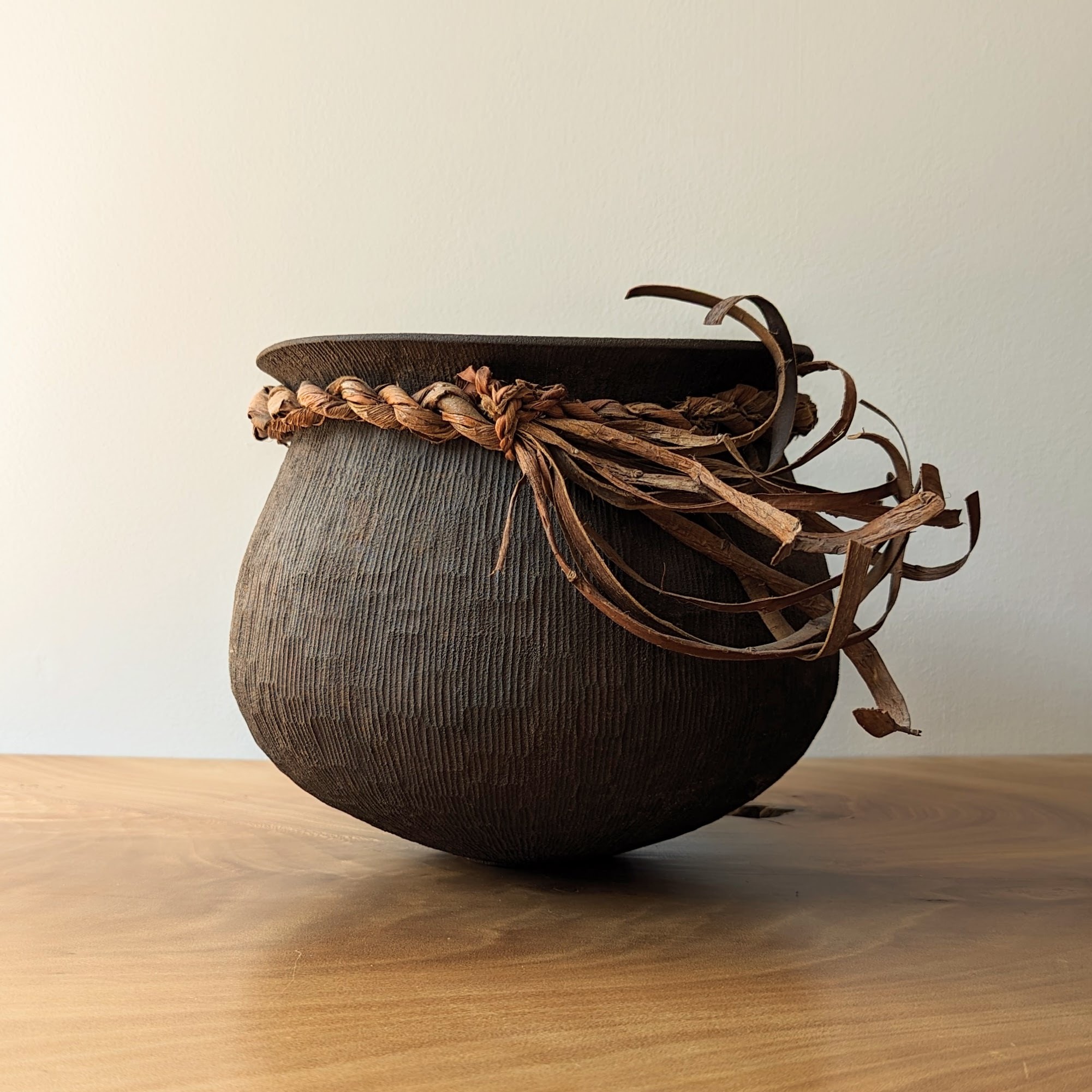 Large dark vessel with string braided around the rim