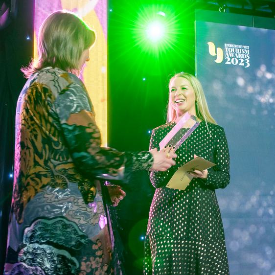 A women with a trophy presents it to another woman