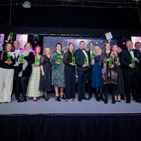 A large group of people holding trophies on a stage.