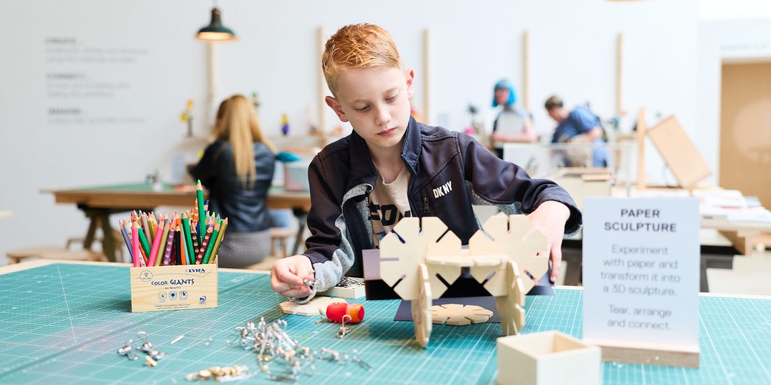 A child builds a sculpture our of interconnecting wooden pieces.
