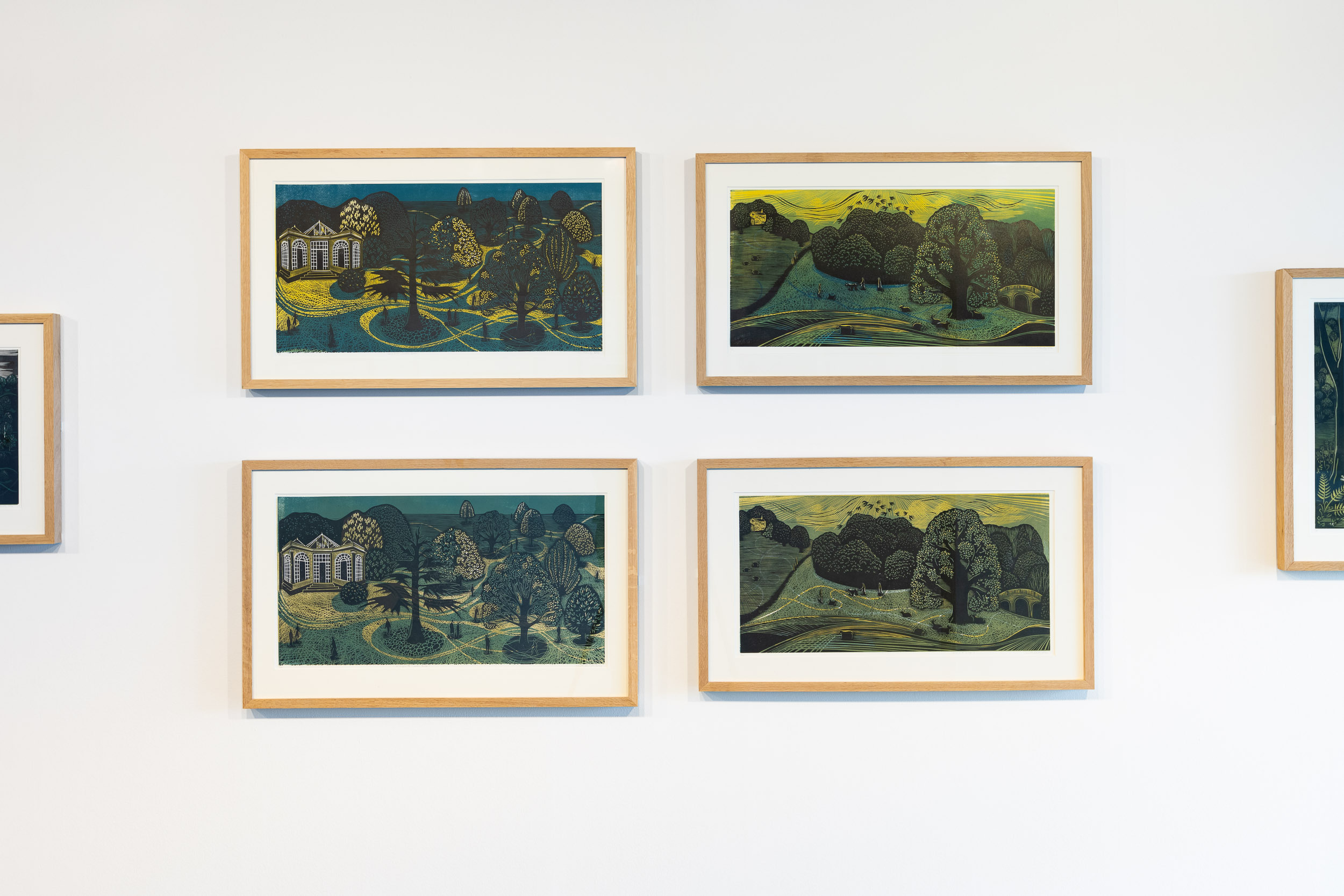 Four framed lino cut prints of landscapes on a white wall.