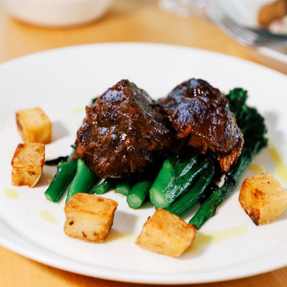 A plate of brazed lamb with greens and potatoes.