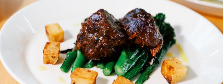 A plate of brazed lamb with greens and potatoes.